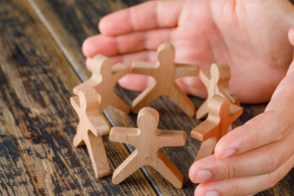 business-success-concept-on-wooden-table-top-view-hands-protecting-wooden-figures-of-people